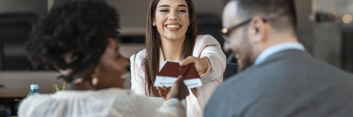 Travel agent giving tickets and passport with visa to tourists. (Photo via dragana991 / iStock / Getty Images Plus)