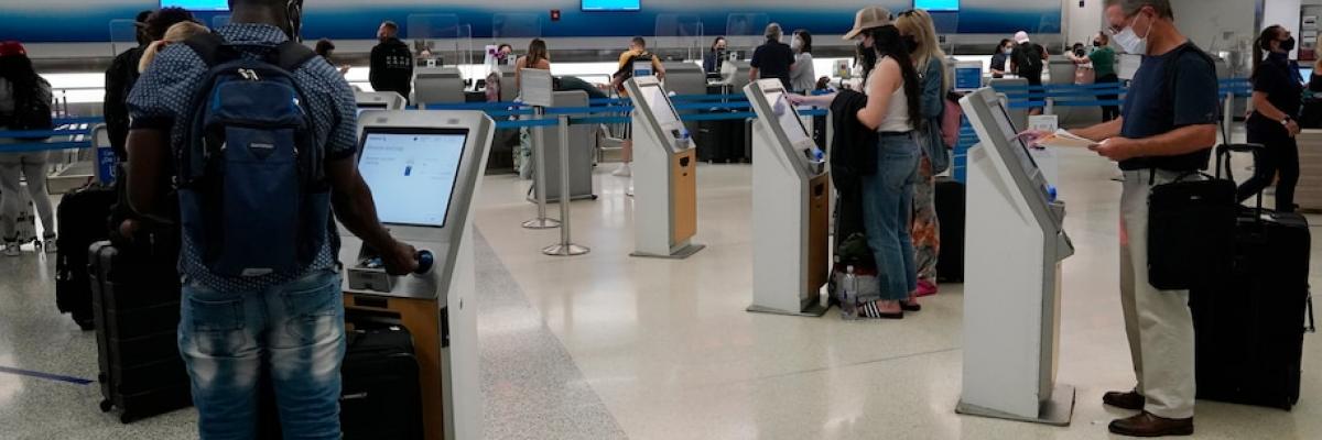 Travelers use self-service kiosks to check in at the American Airlines terminal in Miami. (Marta Lavandier/AP)