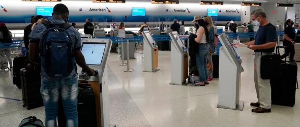 Travelers use self-service kiosks to check in at the American Airlines terminal in Miami. (Marta Lavandier/AP)