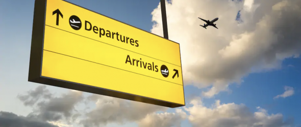 In this image is a hanging departure and arrival sign outside an airport. An airplane is flying in the sky in the background. (iStock)
